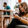 Mädchen sitzt auf dem Sofa und scrollt auf seinem Handy.
