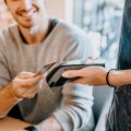 Ein junger Mann bezahlt in einem Café mit Bankkarte.