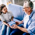 The happy grandfather giving a gift box to a little girl