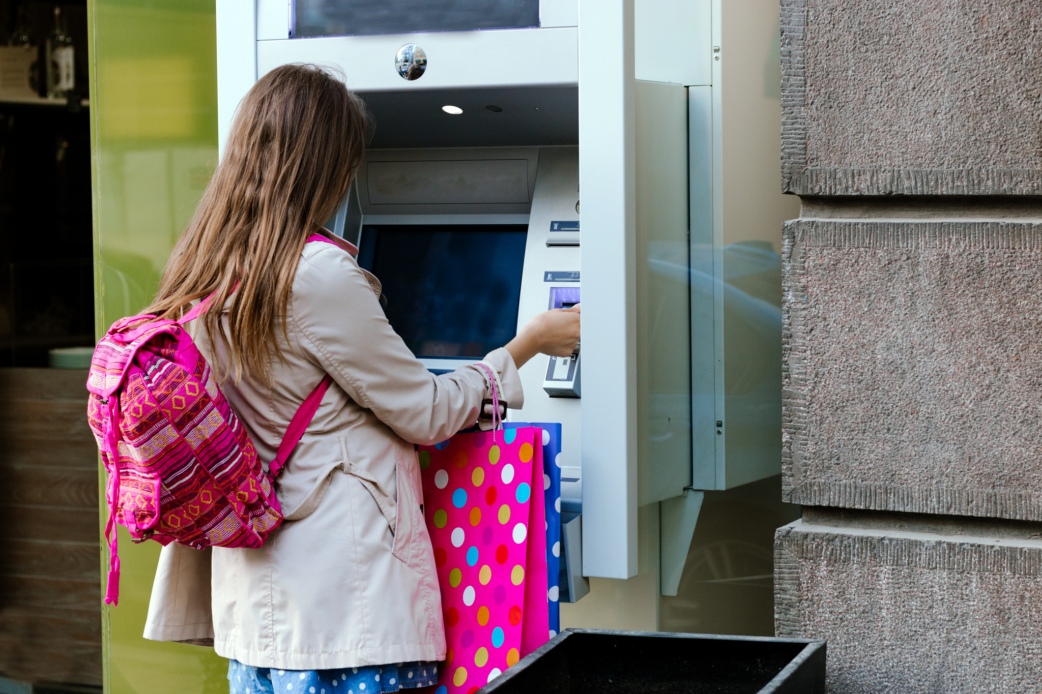 Kind hebt digital ausbezahltes Taschengeld von Bankautomaten ab.