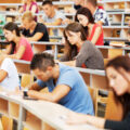 Studierende sitzen in einem Vorlesungssaal und schreiben eine Prüfung.