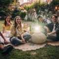 Gruppe junger Erwachsener schaut während den Sommerferien zu Hause im Freien einen Film mit einem Beamer.