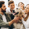 Vierköpfige Familie kuschelt gemeinsam mit ihrem Hund.