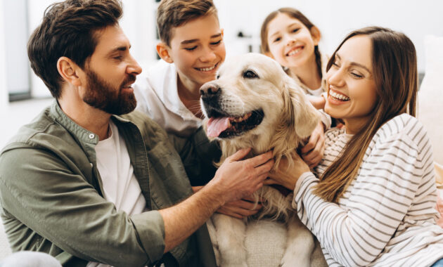 Vierköpfige Familie kuschelt gemeinsam mit ihrem Hund.