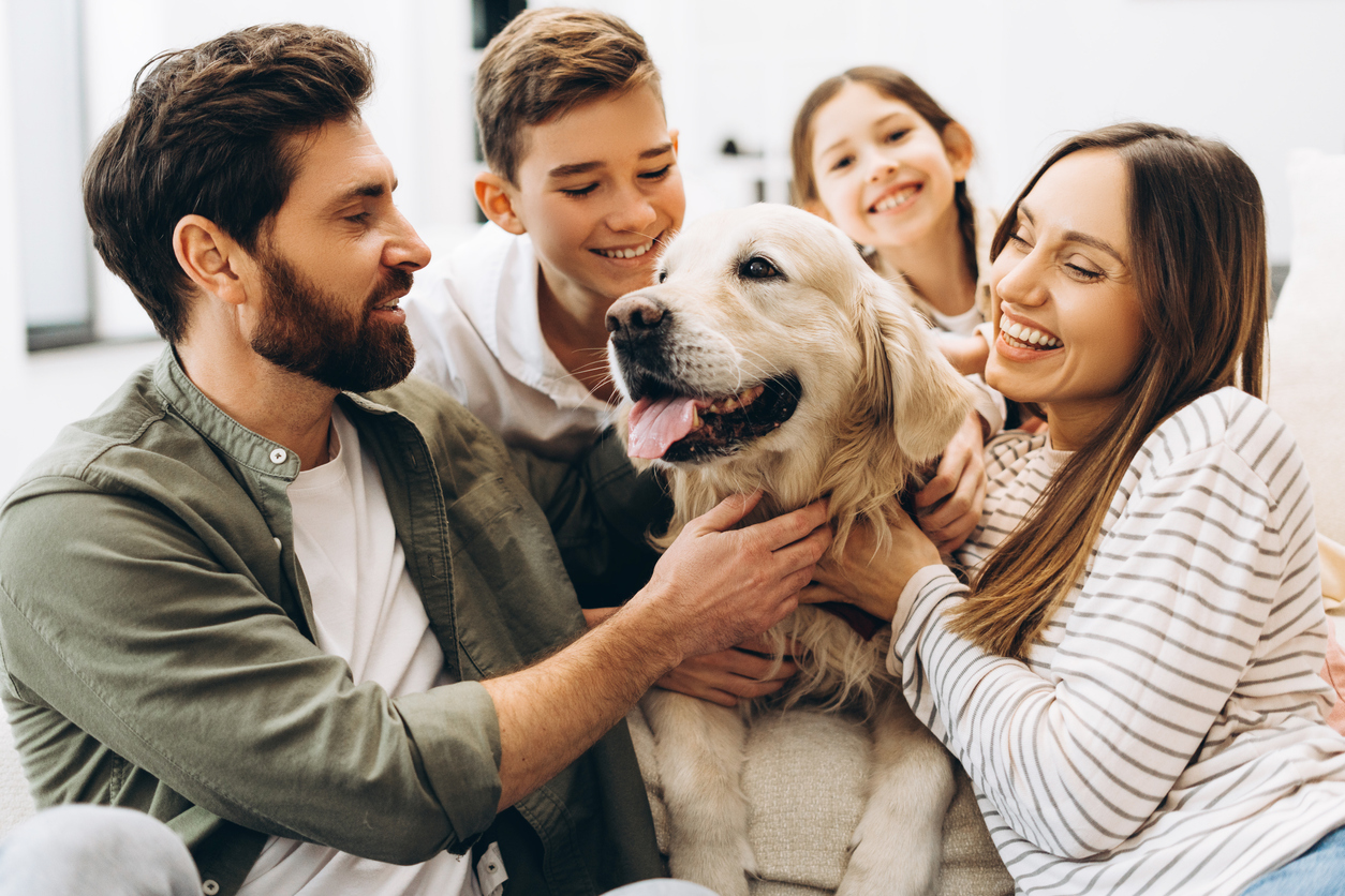 Vierköpfige Familie kuschelt gemeinsam mit ihrem Hund.